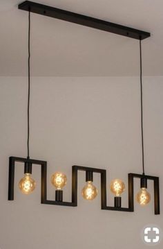 four lights hanging from the ceiling in a room with white walls and black fixtures on it