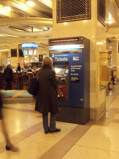 two people are standing in front of a ticket kiosk at an airport terminal