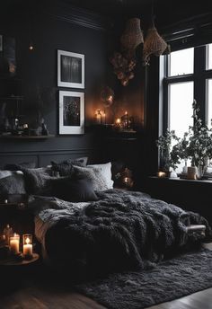 a dark bedroom with candles and pictures on the wall, bed in front of a window