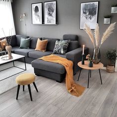 a living room with grey couches and orange throw blankets on the floor, coffee table