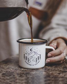 a person pouring coffee into a white mug