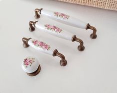 four white knobs with pink flowers on them