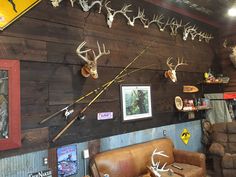 there are many deer heads mounted on the wall in this room with leather couches