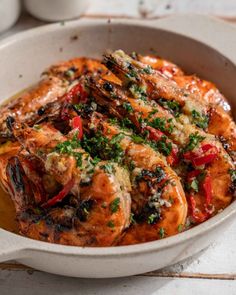 a white bowl filled with cooked shrimp and vegetables