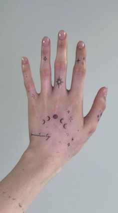 a person's hand with stars and moon tattoos on the palm, in front of a gray background