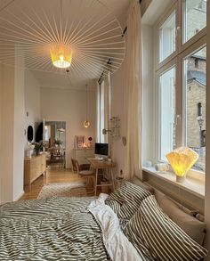 a bed sitting under a window next to a wooden table and chair in a room