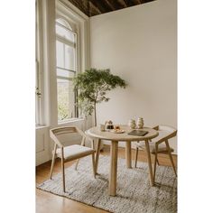 a small table with two chairs and a potted plant in front of a window