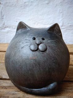 a gray cat shaped vase sitting on top of a wooden table next to a white wall