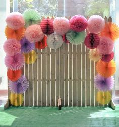 a bunch of paper fans hanging from a wooden fence in front of a large window