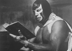 a man wearing a mask and holding a book in his hand while looking at it