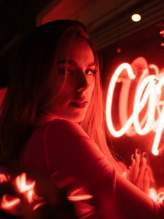 a woman standing in front of a neon sign