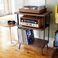 a record player is sitting on top of a shelf next to a table with records