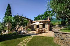 an outdoor dining area in front of a stone building with trees on the other side