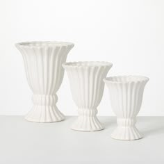 three white vases sitting next to each other