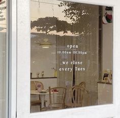 a window that has some chairs and tables in front of it with the words open on them