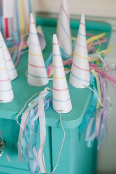 small party hats are on top of a blue table with streamers and streamers