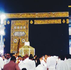 a group of people standing in front of a golden arch with clock faces on it