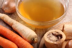 carrots, celery, and other vegetables on a cutting board next to a bowl of oil