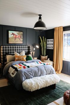 a bedroom with black walls, plaid bedding and green rugs on the floor