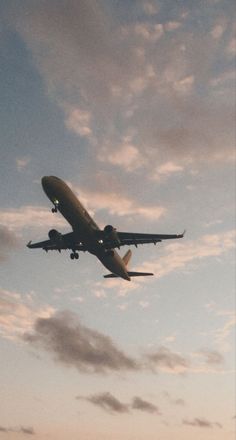 an airplane is flying in the sky at sunset