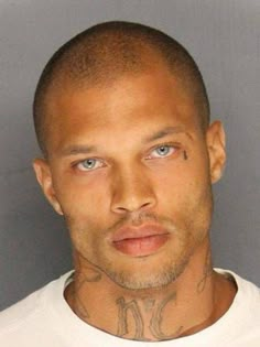 a man with tattoos on his face is mugshoted in front of a gray background