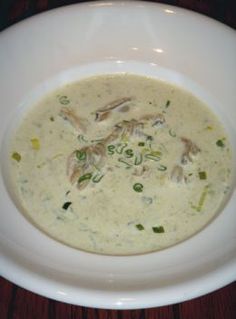 a white bowl filled with soup on top of a wooden table