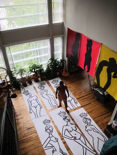 a living room filled with lots of art on the floor next to a large window