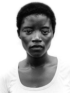 a black and white photo of a woman in a t - shirt looking at the camera