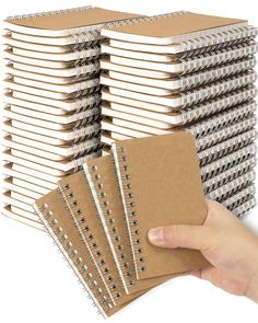 a hand holding a stack of notebooks next to each other