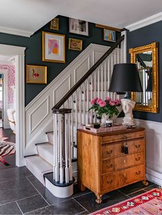 an entryway with stairs and pictures on the wall, along with a chest of drawers