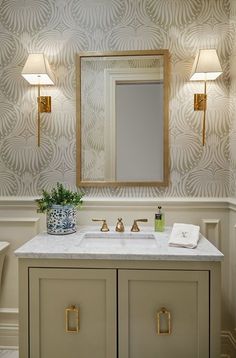 a bathroom with a sink, mirror and two lights on the wall above it's counter