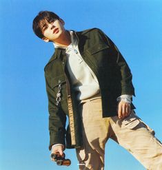 a man standing on top of a skateboard in front of a blue cloudless sky