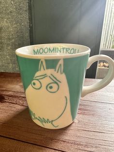 a green and white coffee cup with the words moomiintroli on it