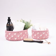 two pink baskets with white hearts on them, one holding a brush and the other containing soap