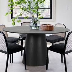 a round table with four chairs around it and a vase full of flowers on top