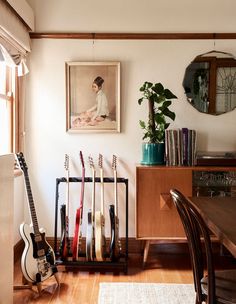 the guitar rack is holding guitars and other musical instruments in this living room with wood flooring