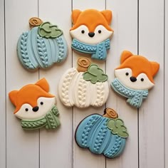 decorated cookies are arranged in the shape of fox and pumpkins on a white wooden surface