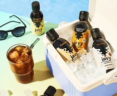 an ice bucket filled with bottles of liquid next to sunglasses and eyeglasses on a table