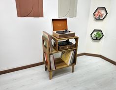 a record player sitting on top of a wooden shelf next to a wall with pictures