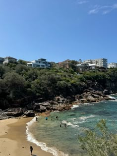 people are walking on the beach in front of houses