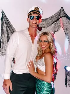 a man and woman pose for a photo in front of a backdrop that looks like bats