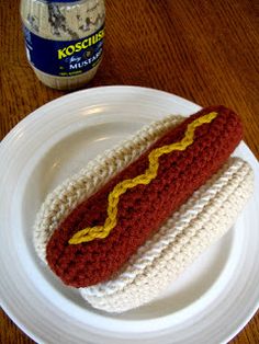 a crocheted hot dog on a white plate