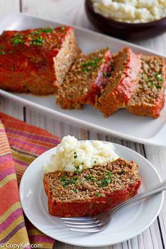 meatloaf and mashed potatoes on a plate with a fork next to it