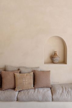 a couch with pillows and a vase on the wall