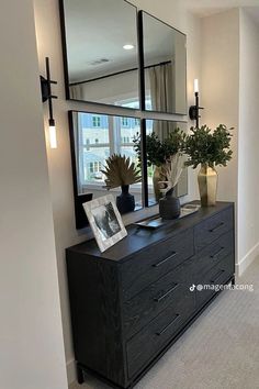 a black dresser topped with a mirror and vases