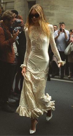 a woman walking down the street in a white dress