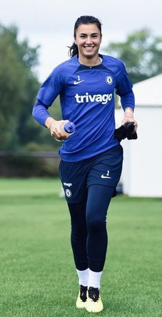 a woman in blue soccer uniform running on grass