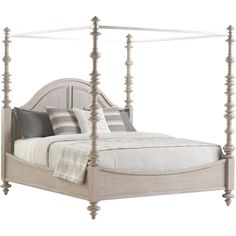 a white bed with four posts and pillows on it's headboard, in front of a white background