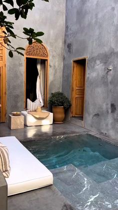 an indoor swimming pool in the middle of a patio with lounge chairs and potted plants