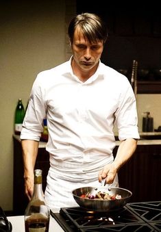 a man standing in front of a stove preparing food